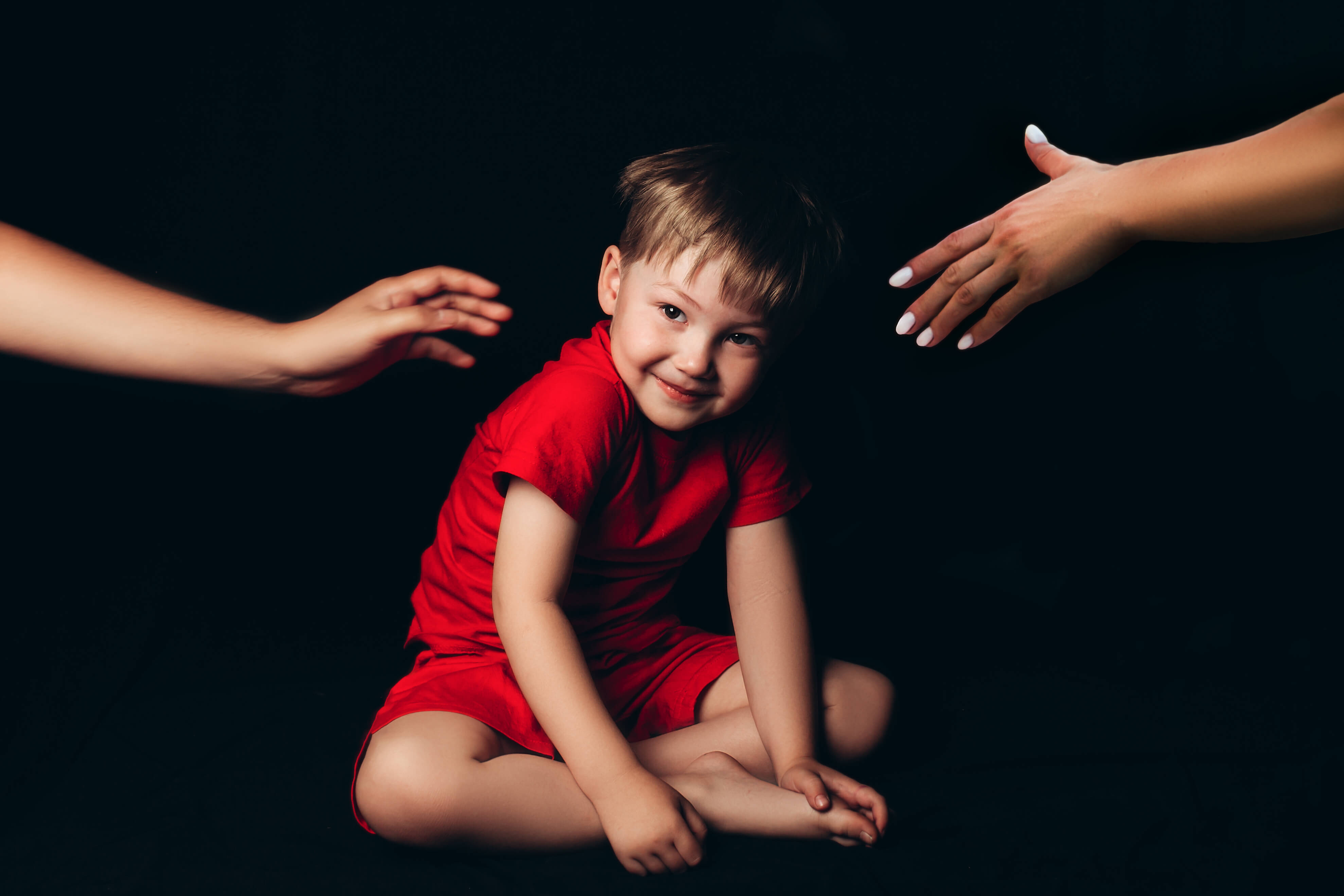 smiling-boy-sitting-on-black-background-between-ma-2025-02-12-05-15-00-utc
